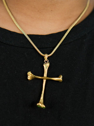 A person wearing a black shirt and the Eternal Relic Necklace, a gothic piece with a gold pendant shaped like two crossed bones.