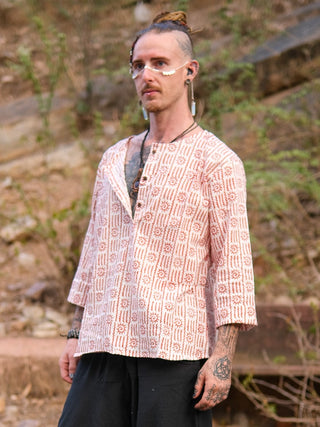 A person with tattoos, facial piercings, glasses, and a bun wears the light pink Moche Kurta (100% cotton, hand block printed) with black pants outdoors against a blurred natural background.
